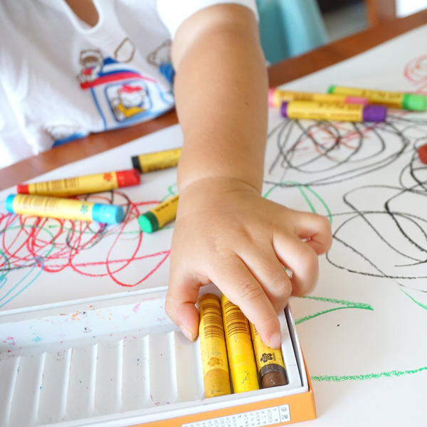 Child drawing a house with pencils